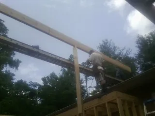 Carpenter setting a ridge beam over a new addition frame — Ice Dam Removal by Roofing Brothers in Bartow