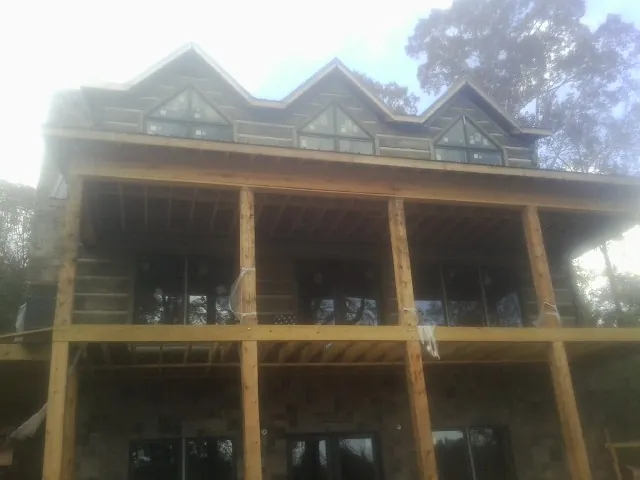 Dormers and porch framing on a large log home under construction — Roof Coating work by our crew in Bartow
