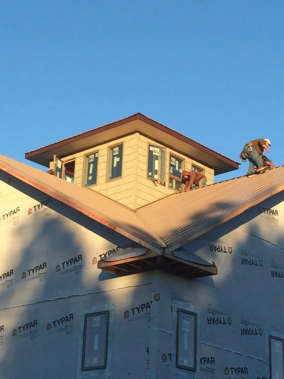 Roofers working around a rooftop cupola on a new metal roof at sunset — Roof Waterproofing in Bartow by Roofing Brothers